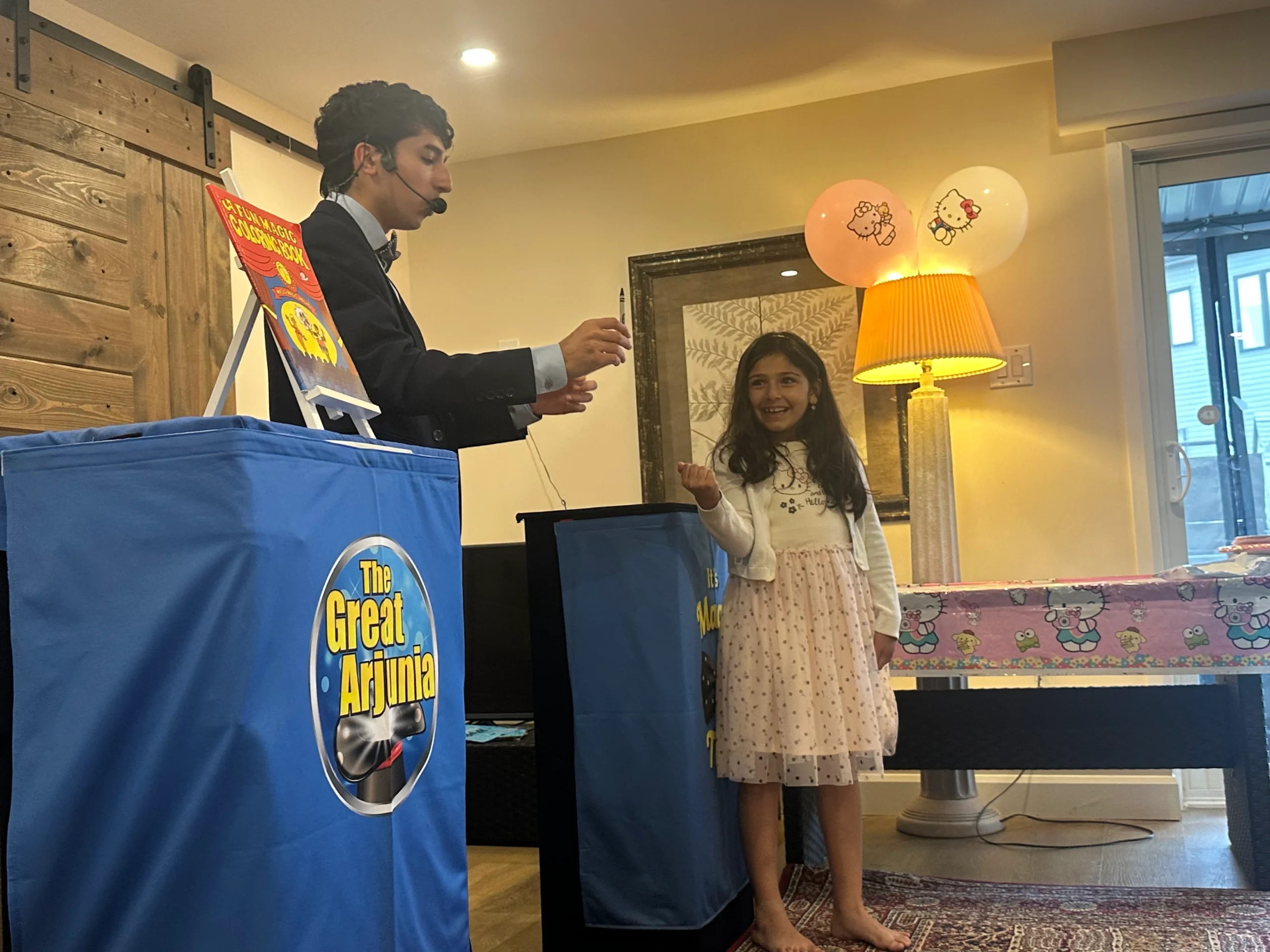 The Great Arjunia performing a magic trick with a crayon for a smiling child.